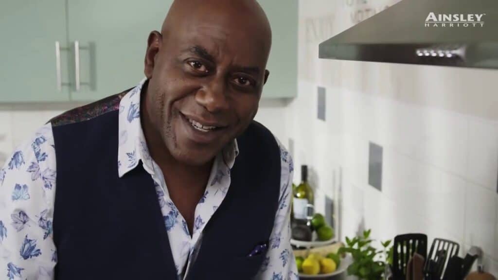 A man smiling in a kitchen with a stove.