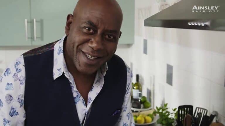 A man smiling in a kitchen with a stove.